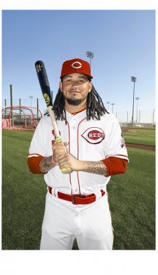 man smiling at the camera holding baseball bat in his hand