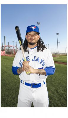 man smiling at the camera holding baseball bat in his hand