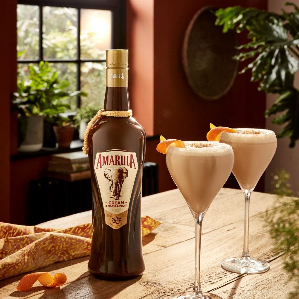 Bottle of Amarula poured in two glasses sitting on a wooden table