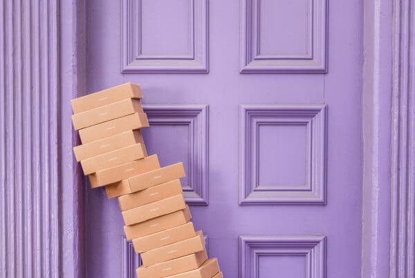 Brown boxes in front of a purple door that are on the verge of toppling over