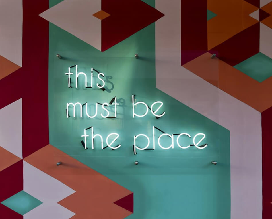 "this must be the place" written on a multicoloured wall