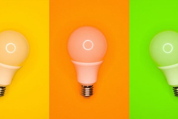 Three light bulbs against bright yellow, orange and green backgrounds