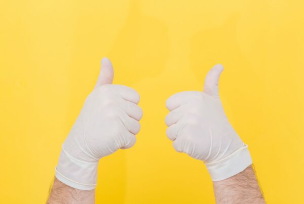 mans hands in surgical gloves against a bright yellow background